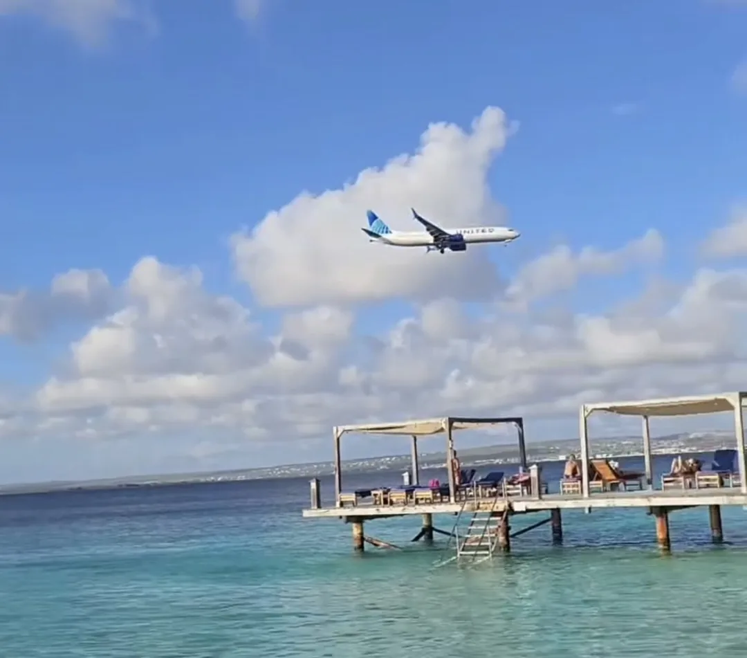 Avião chegando a Bonaire, visto do píer de um restaurante à beira-mar