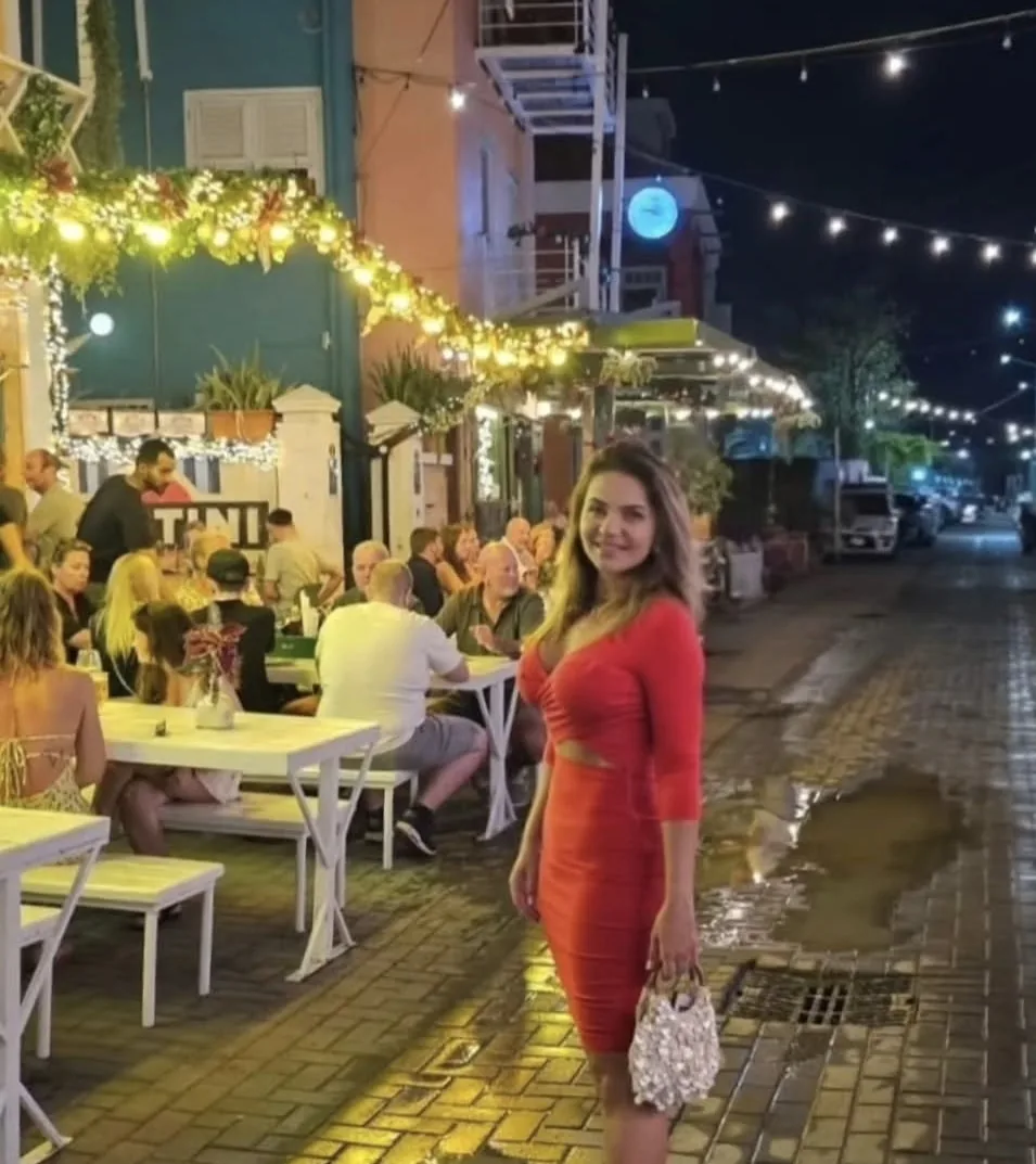 Ju numa rua iluminada de Willemstad, com mesas na calçada e luzes de Natal